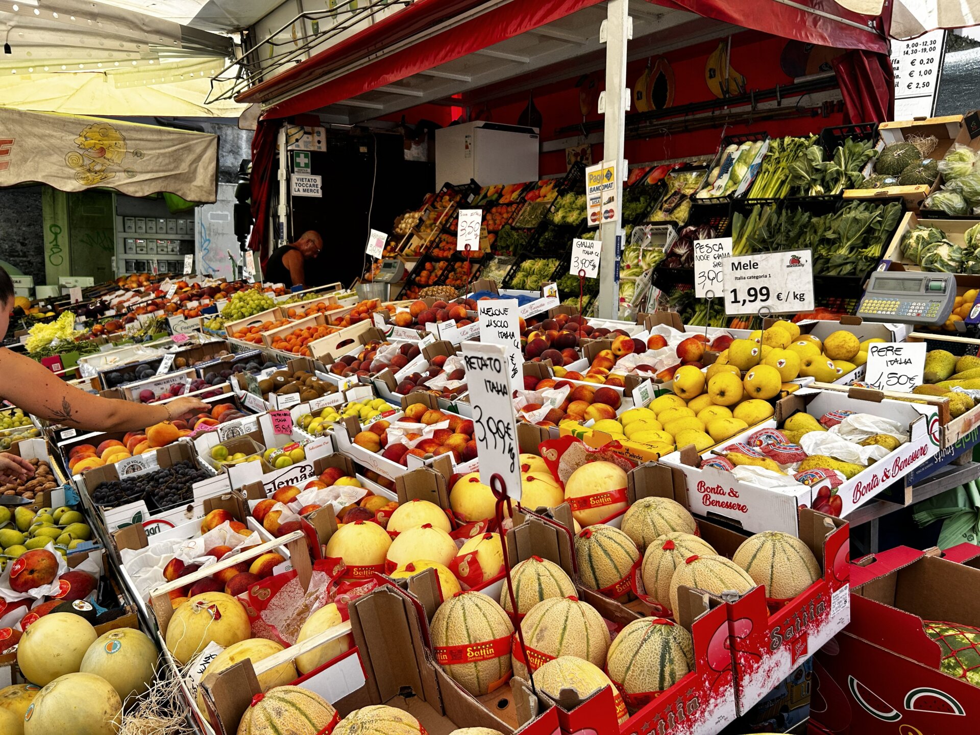 Obst- und Gemüsestand auf dem Wochenmarkt in Luino mit Melonen, Pfirsichen, Birnen und italienischem Gemüse