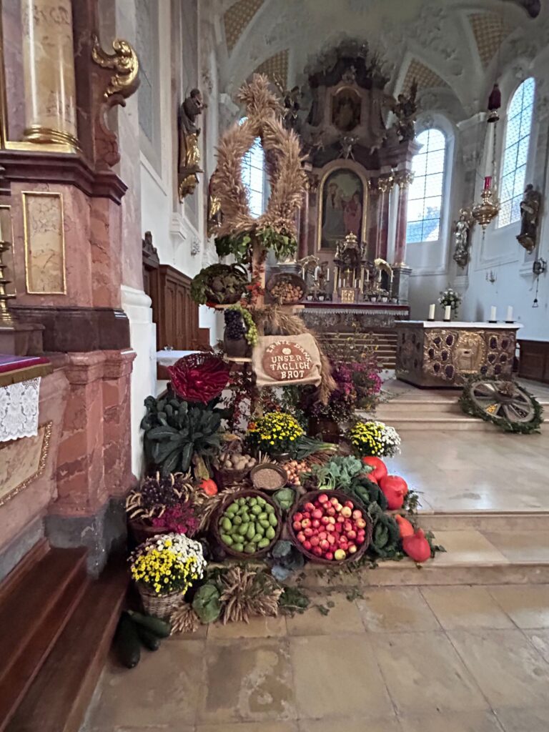 Erntedankschmuck mit Brot, Getreide, Obst, Gemüse und Blumen in der Kirche St. Justina in Bad Wörishofen.